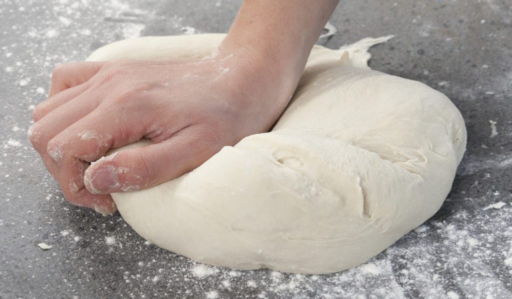 Đầu tiên, bạn nhào bột ở tốc độ thấp trong 2 - 3 phút. Khi thấy nguyên liệu tạo thành khối thì tăng tốc độ vừa và nhồi trong khoảng 8 - 10 phút đến khi bột thành khối dẻo mịn, đàn hồi.  Sau đó bạn lấy bột ra ngoài và nhồi lại bằng tay trong 1 phút.  Lưu ý: ⊗ Nếu không có máy trộn bột thì bạn nhào bột bằng tay theo cách sau  Bạn gấp đôi bột rồi dùng mu bàn tay miết bột ra xa, xoay bánh 90 độ rồi tiếp tục lặp lại 2 động tác trên khoảng 15 - 20 phút. Nhào cho đến khi bột không còn dính tay, dẻo mịn, kết thành một khối là đạt yêu cầu.